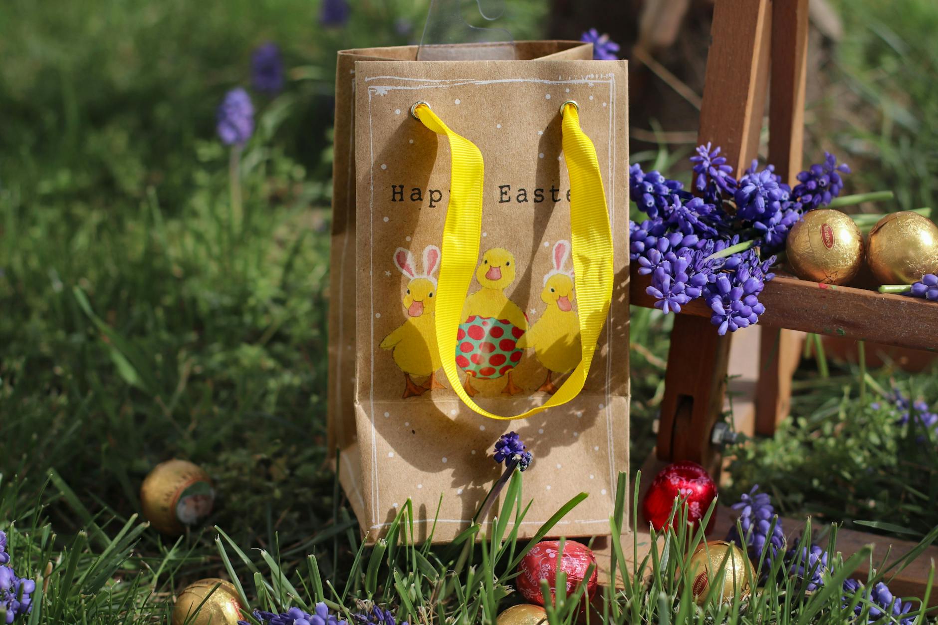 a gift bag with easter illustration standing among easter eggs on the grass