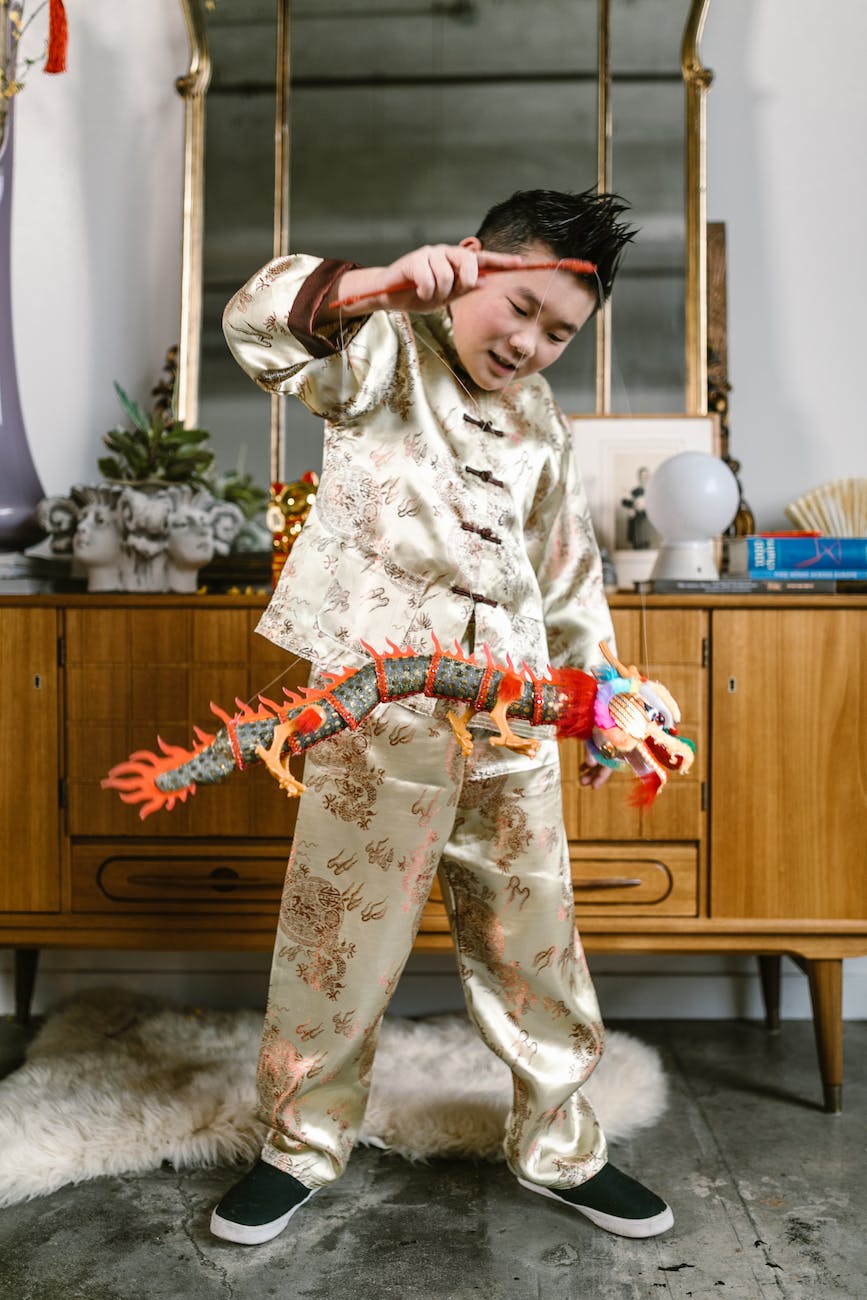 a boy in traditional clothing playing with a toy dragon