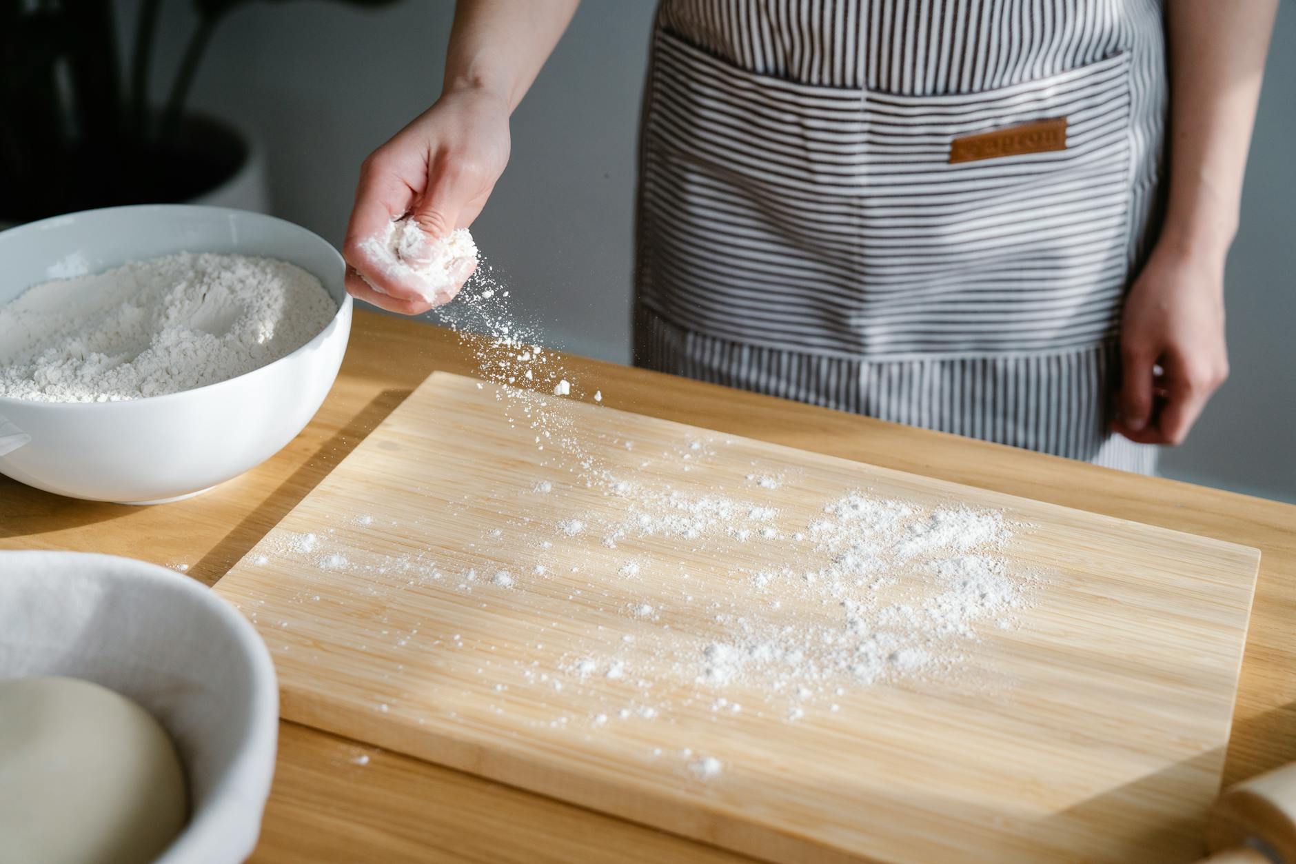 close up of person spreading flour on a cutting board